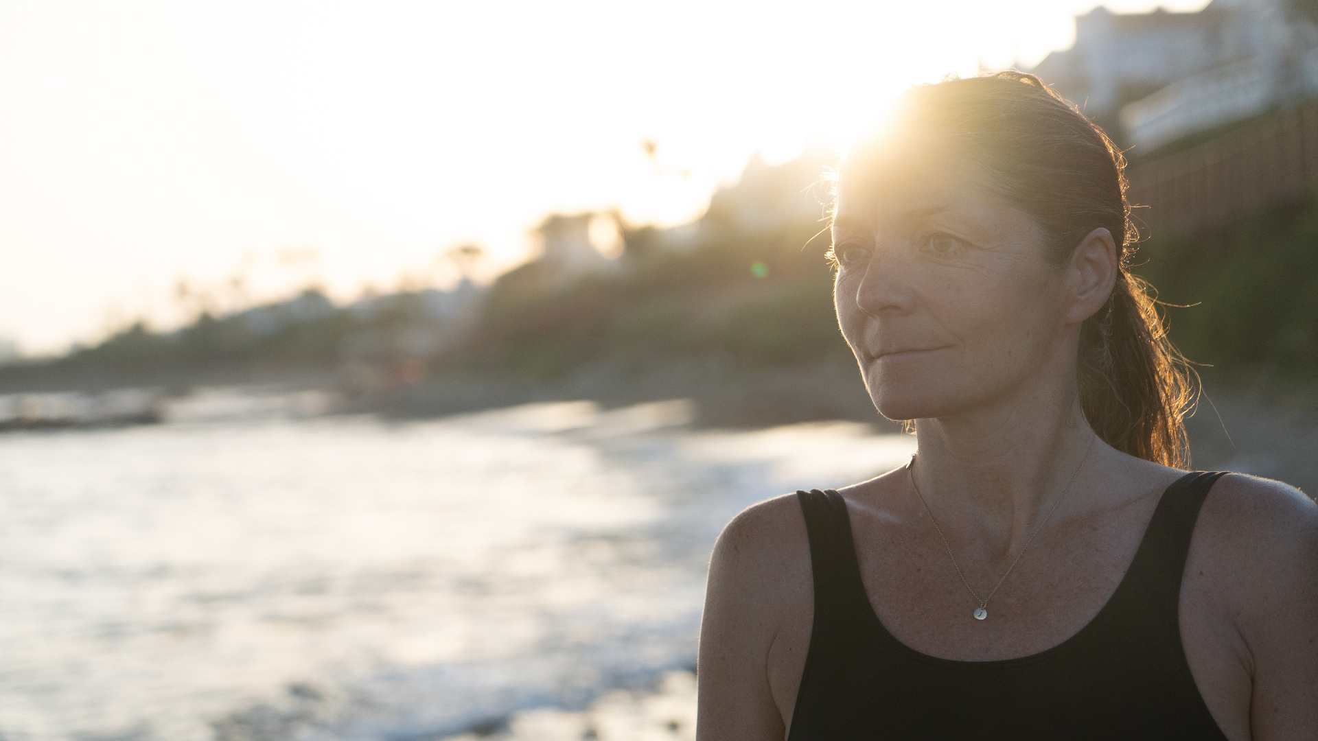 Mujer practicando meditación junto a una ventana con luz cálida